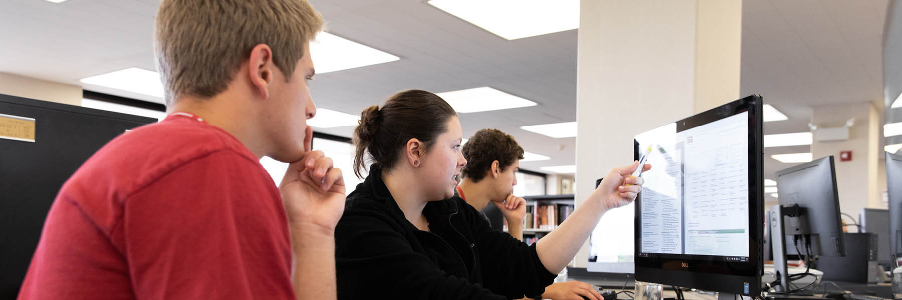 An advisor points out something on a computer screen to a student.